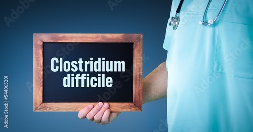 Clostridium difficile. Doctor shows sign/board with wooden frame. Background blue photo