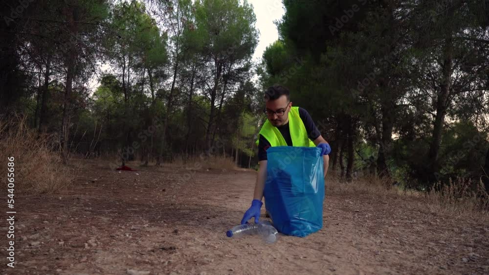 Guardabosque recogiendo plástico en la montaña. Video horizontal 4K. 