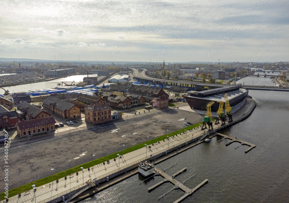 A view of the city from above. Aerial view. Agglomeration, streets, river, road, buildings, machinery, cranes, shipyard.