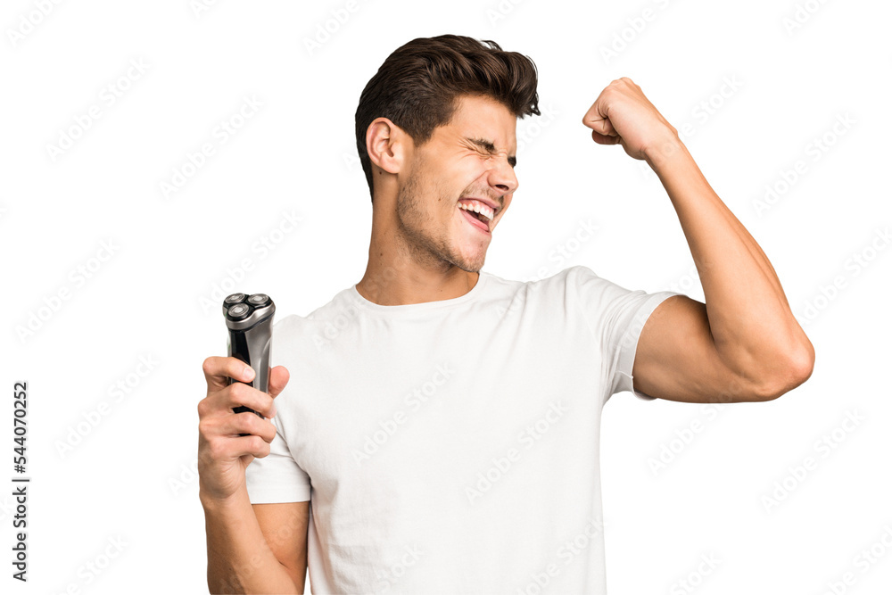 Young caucasian man holding a razor isolated raising fist after a victory, winner concept. Young caucasian man holding a razor isolated raising fist after a victory, winner concept.