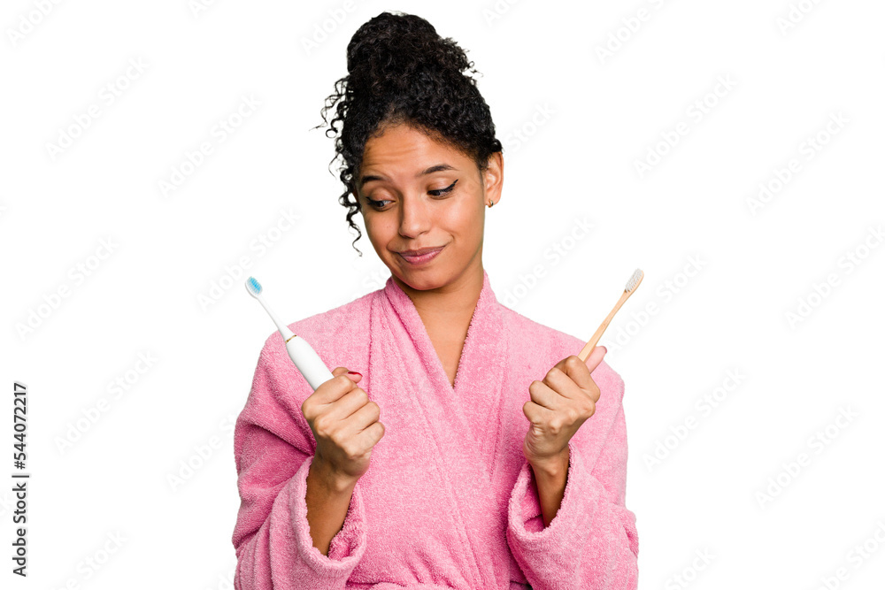 Young african american woman doing a comparison between a normal toothbrush and electrical isolated from background Young african american woman doing a comparison between a normal toothbrush and electrical isolated from background