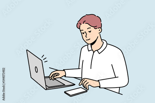 Young businessman sit at desk work on laptop use cellphone. Male employee multitask busy with electronic gadgets on table in office. Vector illustration. 