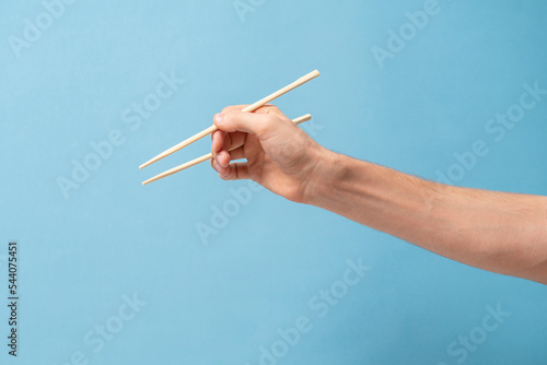 Fototapeta Naklejka Na Ścianę i Meble -  hand holds wooden asian food chopsticks
