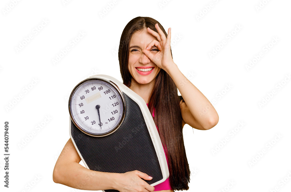 Young caucasian woman holding a scale isolated excited keeping ok gesture on eye. Young caucasian woman holding a scale isolated excited keeping ok gesture on eye.