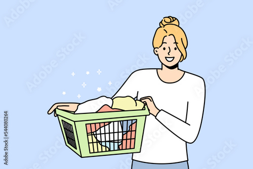 Smiling young woman with basket with clothes going to laundry. Happy girl cleaning clothing in laundromat. Vector illustration. 