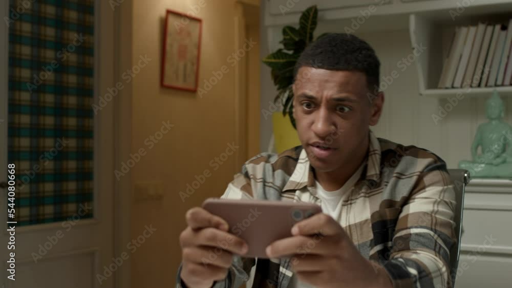 Man loosing video game using smartphone. Upset African American man lost mobile phone game at home. Man loosing video game using smartphone. Upset African American man lost mobile phone game at home.