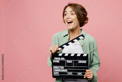 Foto Young surprised happy woman 20s wear green shirt white t-shirt holding classic black film making clapperboard isolated on plain pastel light pink background studio portrait