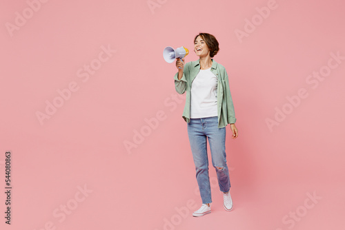Full body young woman 20s she wear green shirt white t-shirt hold scream in megaphone announces discounts sale Hurry up isolated on plain pastel light pink background studio. People lifestyle concept.