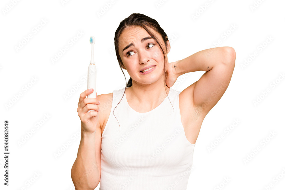 Young caucasian woman holding electric toothbrush isolated on green chroma background touching back of head, thinking and making a choice. Young caucasian woman holding electric toothbrush isolated on green chroma background touching back of head, thinking and making a choice.