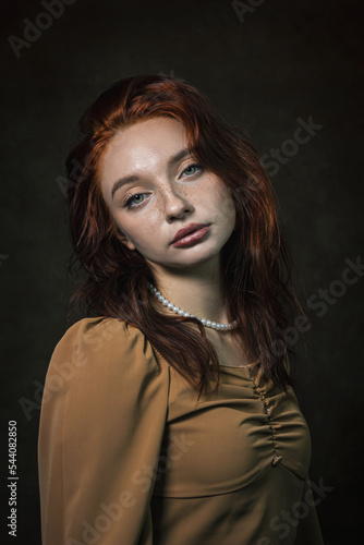 Portrait of a beautiful red-haired girl on a dark background