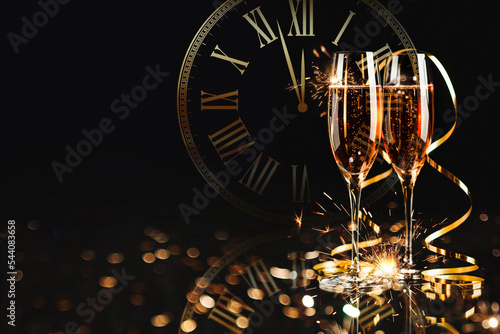 Obraz na płótnie Happy New Year! A golden bucket with champagne, two glasses and a golden serpentine against the background of a clock face