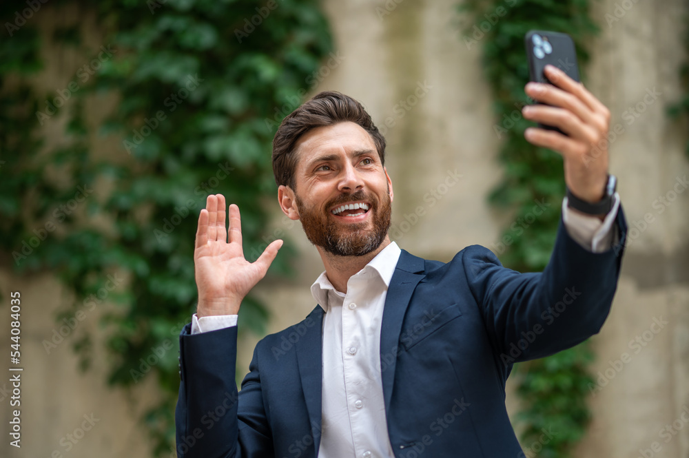 Smiling businessman having a video call and looking excited Smiling businessman having a video call and looking excited