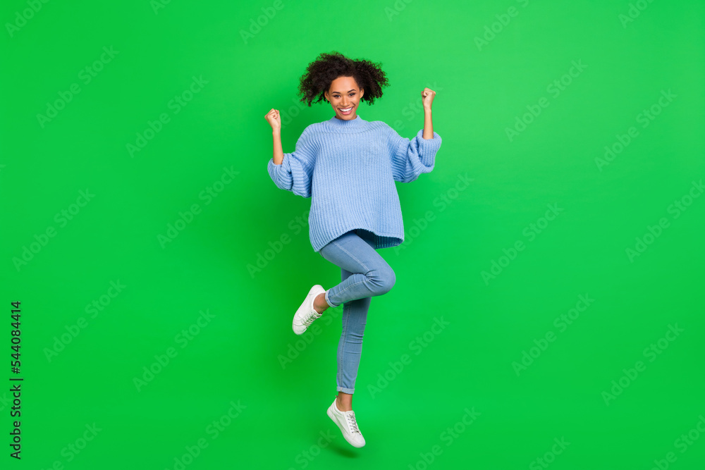 Full length photo of delighted excited person jump raise fists success isolated on green color background Full length photo of delighted excited person jump raise fists success isolated on green color background