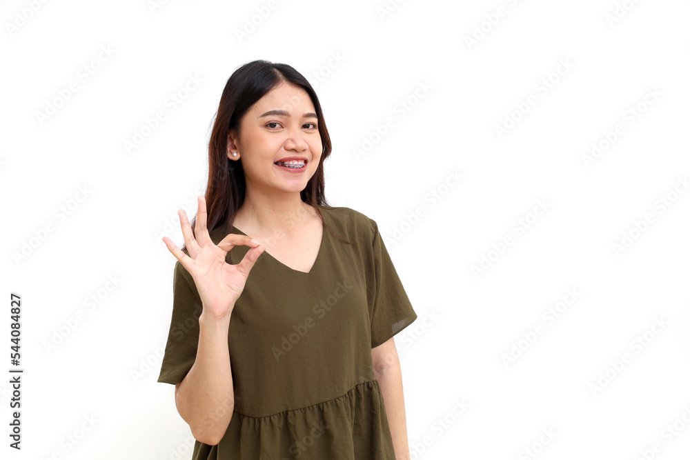 Portrait of happy young asian woman standing while showing okay hand gesture. Isolated on white background Portrait of happy young asian woman standing while showing okay hand gesture. Isolated on white background