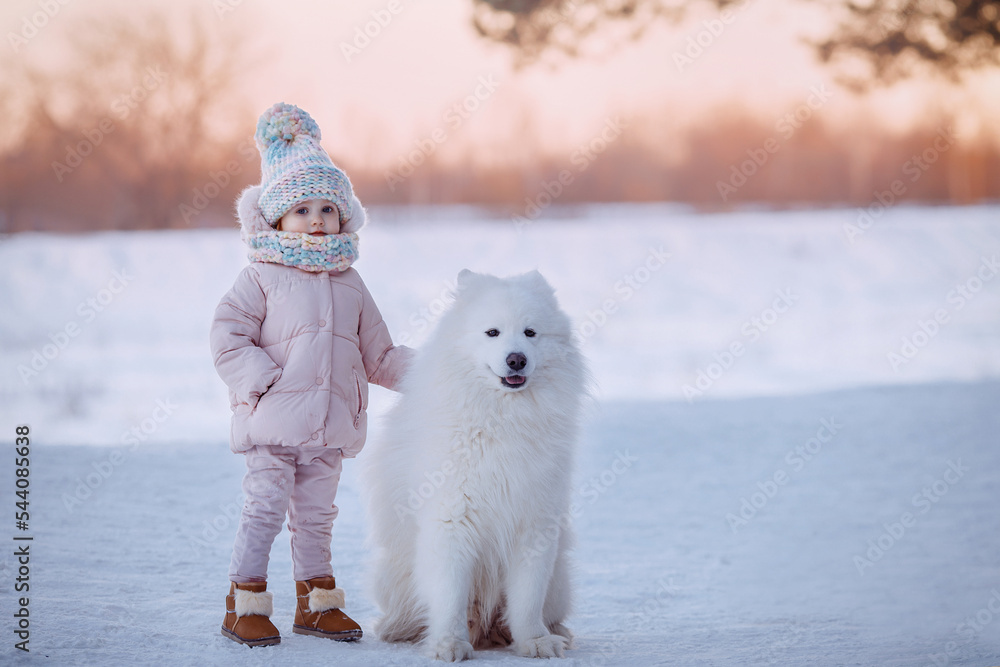 Charming little girl in a warm coat with a dog