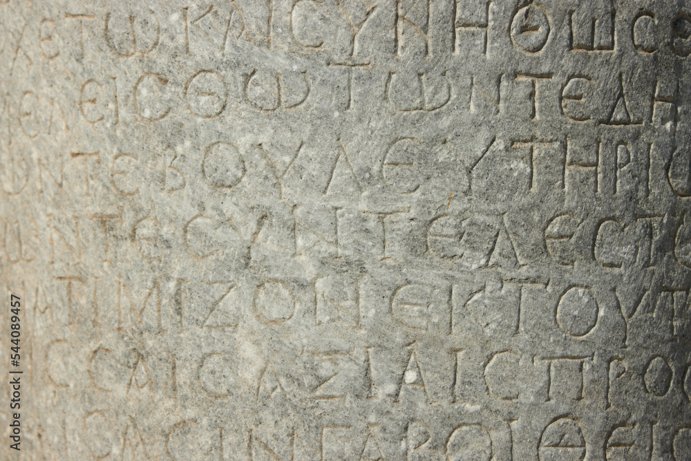 The ancient inscription is on the antique column or the wall. Ancient greek language 
