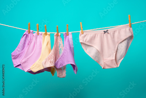 Female panties hanging on rope against blue studio background