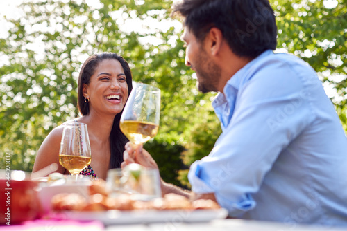 Couple Eating Outdoor Meal And Drinking Wine In Garden At Home Together