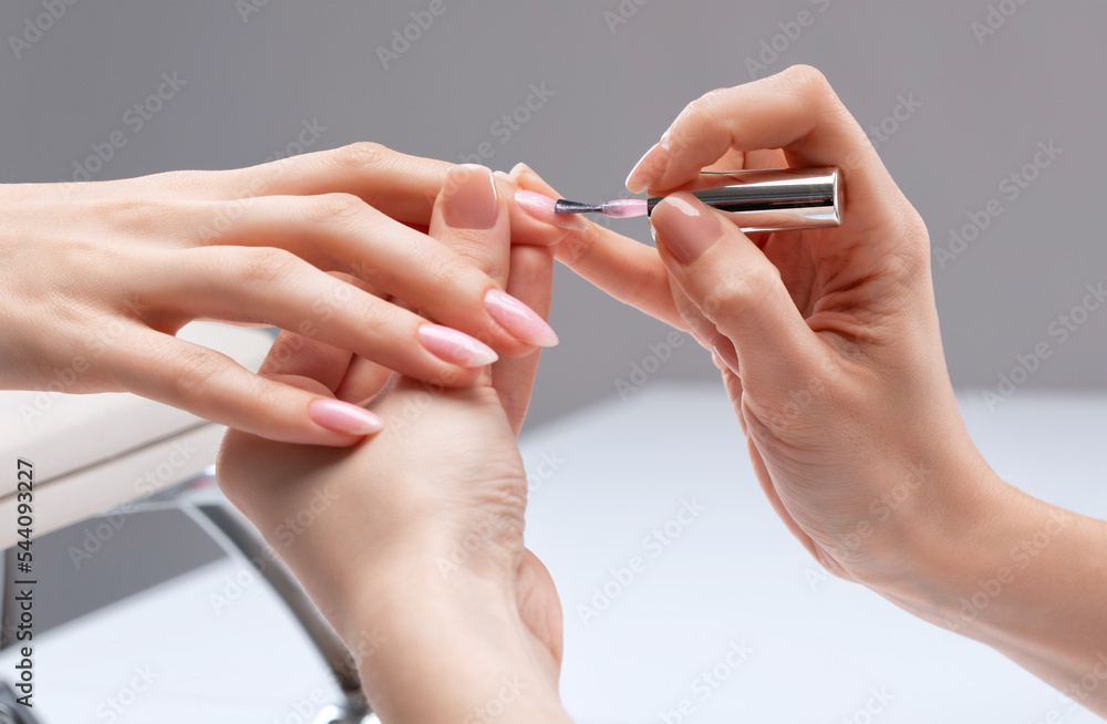 The master of the manicure coats nails with gel polish in the beauty salon. Professional care for hands. The master of the manicure coats nails with gel polish in the beauty salon. Professional care for hands.