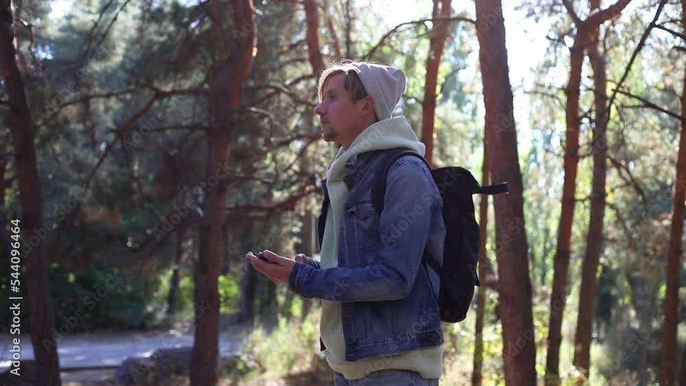 Young man tourist hiking in forest searching navigation in phone looking for way Young man tourist hiking in forest searching navigation in phone looking for way