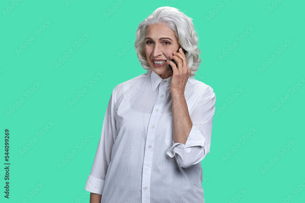 Portrait of aged old woman talking on phone. Isolated over pastel green background. Portrait of aged old woman talking on phone. Isolated over pastel green background.
