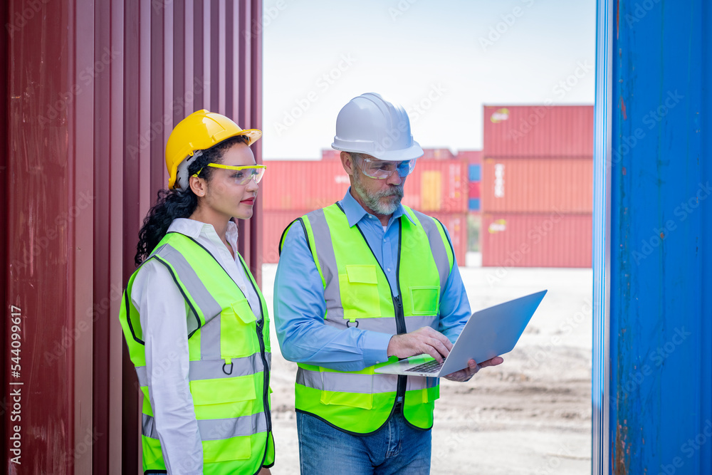Engineer working in the construction container dock yard checking and inspection containers data on laptop program is container shipping Logistics business concept. Engineer working in the construction container dock yard checking and inspection containers data on laptop program is container shipping Logistics business concept.