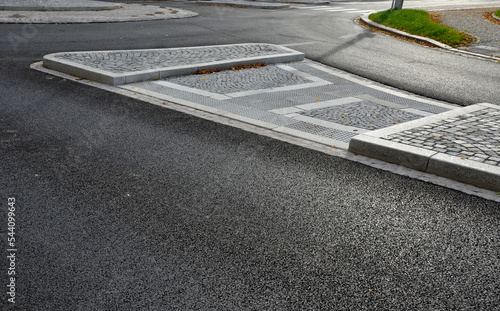 planting at the crossroads at crossing. recumbent junipers in regular raster. flowerbed is mulched with bark chips. granite curbs and road markings, mosaic, grid, blind, bumps, islands, curved, edge photo