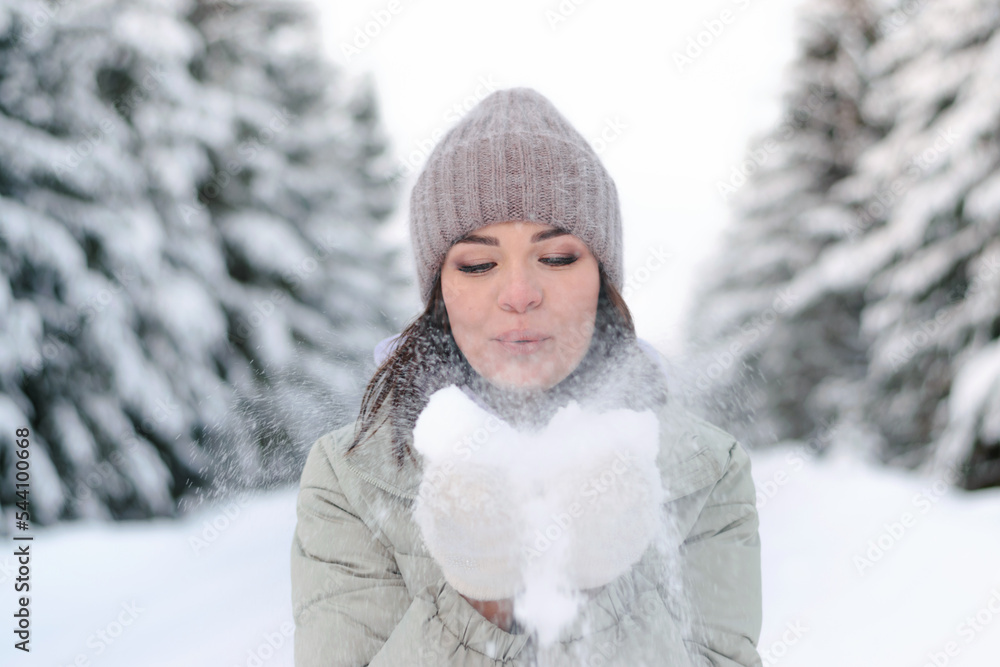 Young beautiful woman blowing snow off the hand.Winter outdoor activity, winter holidays.Selective focus, close up. Young beautiful woman blowing snow off the hand.Winter outdoor activity, winter holidays.Selective focus, close up.
