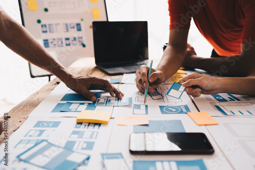 Ux developer and ui designer brainstorming about mobile app interface wireframe design on table with customer breif and color code at modern office.Creative digital development agency