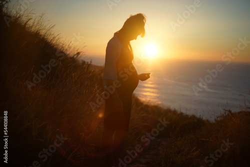 Pregnant woman enjoys the magical sunset 