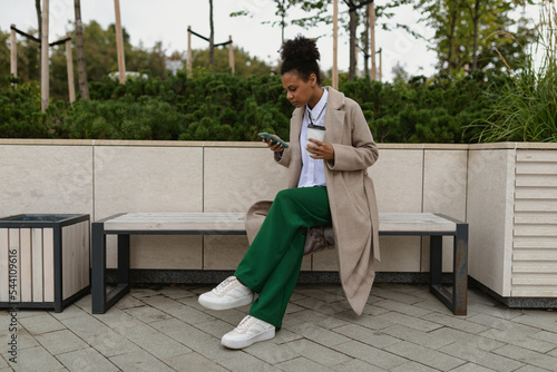 strong american woman student surf the internet on the phone with a cup of coffee in her hands