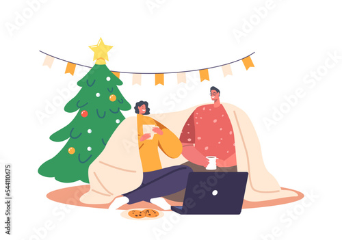 Young Loving Couple Sitting in on Floor Living Room Drinking Tea, Chatting, Watching Movie on Laptop during Christmas