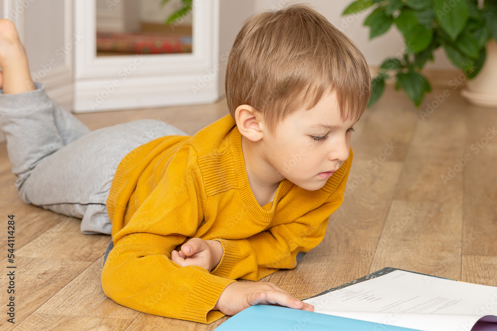 A little boy is reading sitting on the floor. A little boy is reading sitting on the floor.