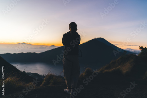 Unrecognizable woman admiring nature from grassy hill