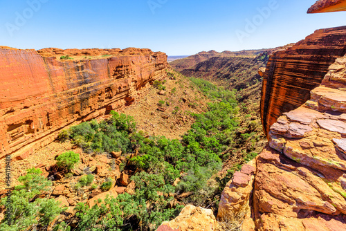 Watarrka National Park, Australia Outback Red Center, Northern Territory. Edge of Kings Canyon with tall walls, red sandstone and Garden of Eden with gum trees and bush vegetation.
