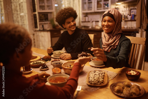 Photography Happy black Muslim woman eating with her family at dining table.