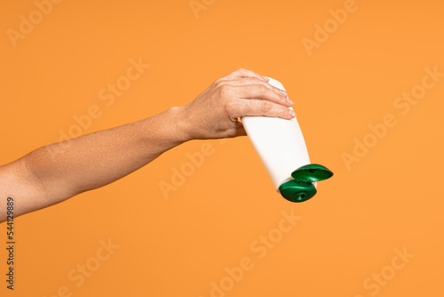 concept of running out of shampoo. white bottle with an open lid upside down in hand