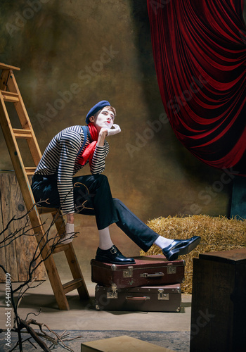 Fototapete Vintage portrait of male mime artist expressing sadness and loneliness over dark retro circus backstage background