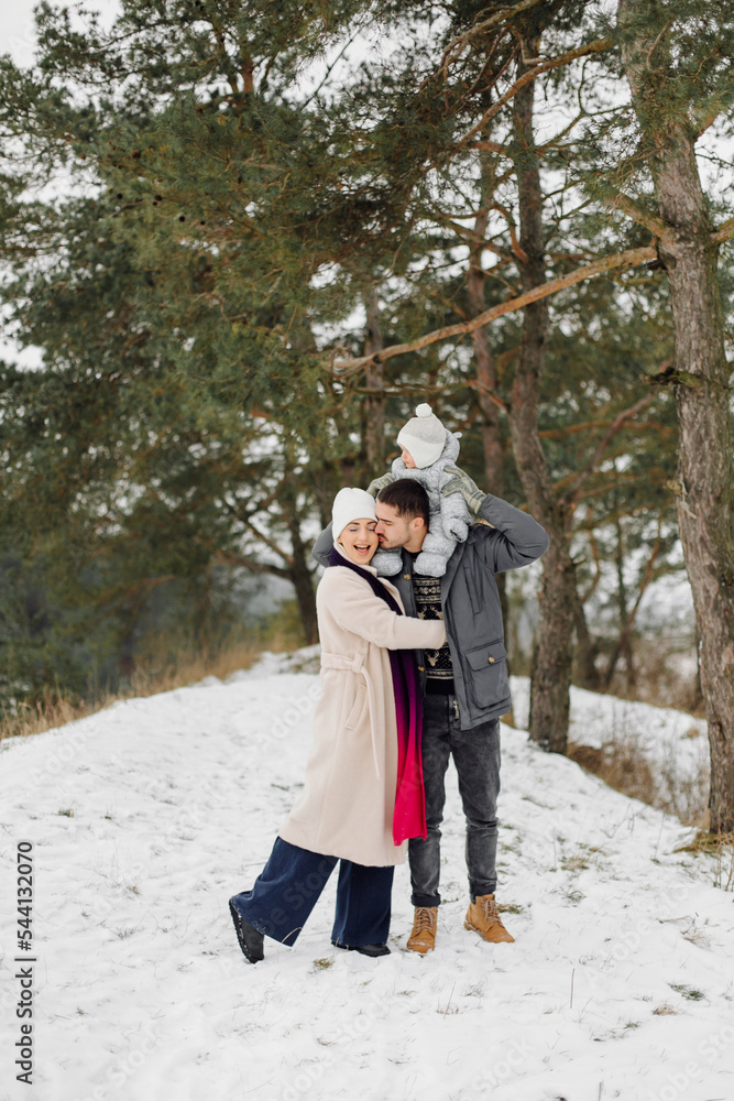 Family walking in the snow having fun in winter park on a bright day hugging each other and smiling Family walking in the snow having fun in winter park on a bright day hugging each other and smiling