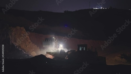 Coal mining dump trucks and excavators working at night, slow motion