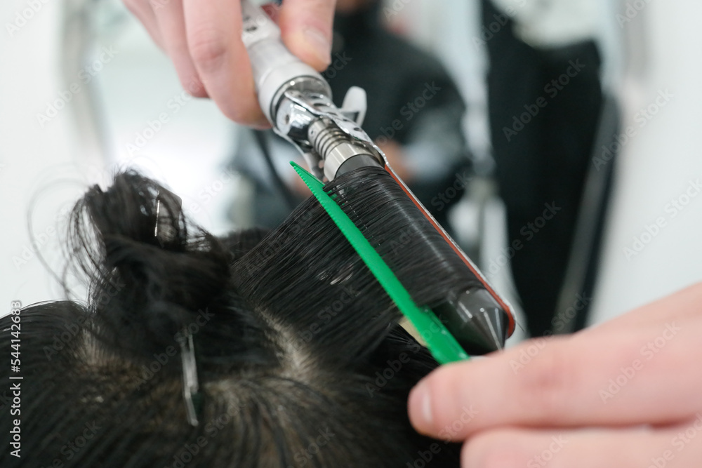 Naklejka premium Close-up of a man's hair perming with a hairdressing tool