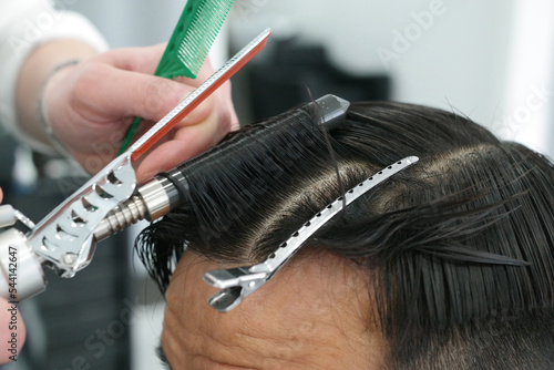 Fotografie Close-up of a man's hair perming with a hairdressing tool