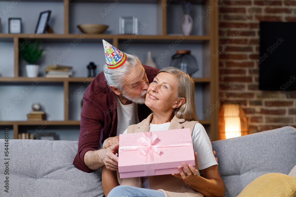 Caring old husband giving romantic birthday present to excited mature