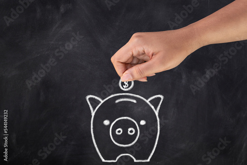 Close-up of hand on black chalkboard with drawn little pig.