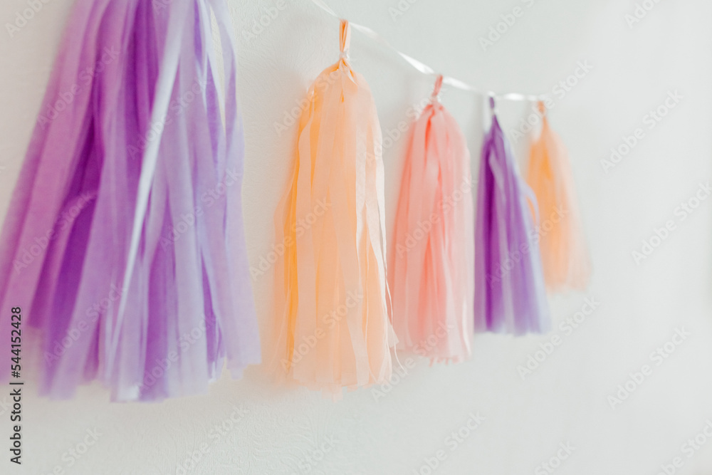 Tissue paper tassel garland. Pastel colors on the white background. Decoration for party. Minimalist style, copy space