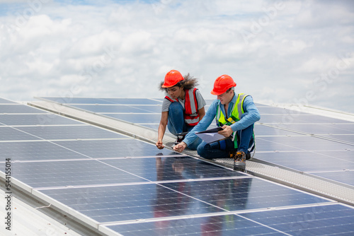 technician engineer working on checking maintenance service with solar batteries near solar panels at sunny day in solar power plant station on rooftop, electricity energy of photovoltaic industrial