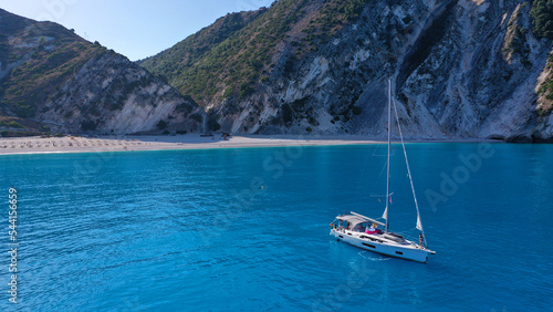 Aerial drone photo of sail boat anchored in paradise beach of Myrtos with crystal clear turquoise sea surrounded by steep cliffs photo