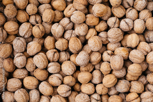 Heap of raw walnuts close-up as a background.