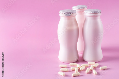 Konstfotografi Three bottles of milk yogurt (kefir) and capsules with probiotic on a pink background