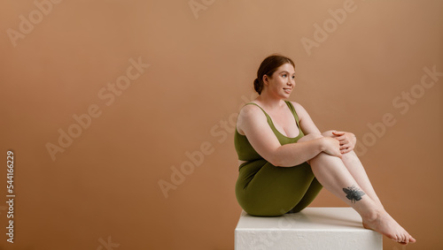 White young woman with ginger hair smiling while siting on cube